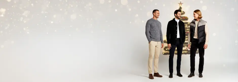 Tři muži oblečení ve stylových, ležérních outfitech stojí společně před světlým pozadím a předvádějí moderní módní trendy.